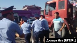 Сотрудники полиции уводят человека после его попытки воспрепятствовать сносу торговых точек на центральном рынке. Шымкент, 30 июля 2018 года.