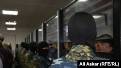 Сотрудники спецназа стоят напротив обвиняемых по делу о вооруженных нападениях 5 июня. Актобе, 28 ноября 2016 года.