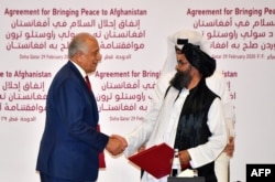 د افغان سولې لپاره د امريکا ځانګړی استازی زلمی خليزاد او د طالبانو د قطر دفتر مشر ملا غني برادر د سولې پر تړون د لاسليک وروسته روغبړ کوي. انځور-ارشېف