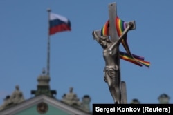 ჯვარცმაზე შებმული ცისარტყელას ფერებიანი ლენტი ​ერმიტაჟის თავზე, რუსეთის დროშის გვერდით.