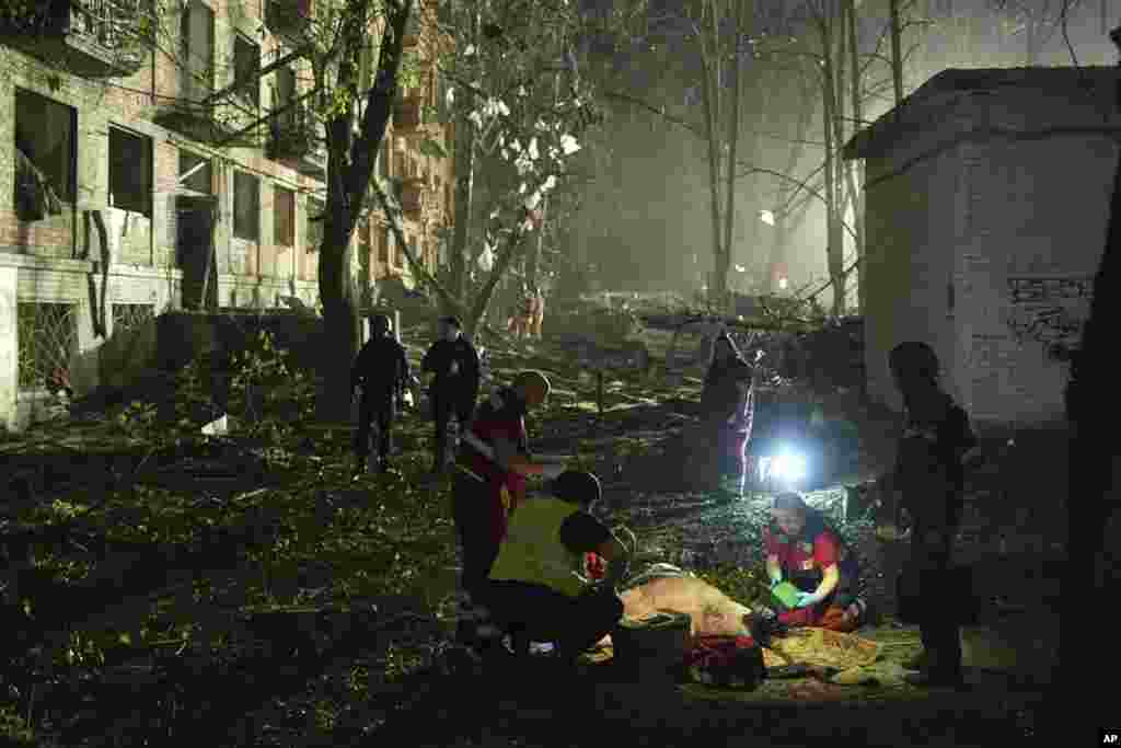 Mjekët ukrainas e mjekojnë një burrë të plagosur pas një sulmi me raketë balistike ruse në Kiev.