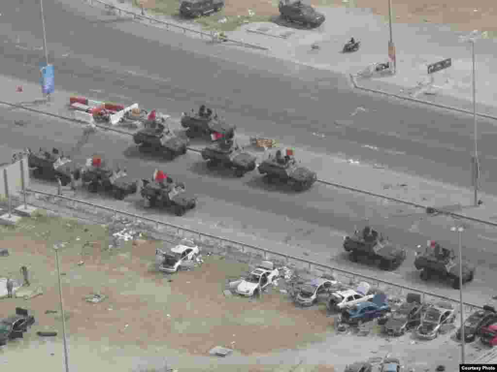 Бахрейн. Ордо шаар Манаманын көчөлөрүндөгү аскер унаалары. Бермет аянтынан бир көрүнүш. 6-сүрөт. 17.3.2011. Nick. - 2011-жылдын 17-мартында (бейшембиде) Бахрейн падышалыгынын коопсуздук күчтөрү Манама шаарынын көчөлөрүн жана аянттарын көзөмөлдөөсүн улантты.  Алар шийи араптар басымдуулук кылган демонстранттарды 16-мартта күч менен таркаткан. Ишкер Ник “Азаттыкка” жиберген сүрөттөрдөн. Манама ш., Бахрейн. 17.03.2011. № 6-сүрөт.