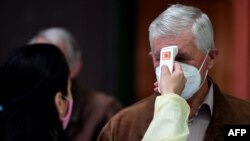 Медицинска сестра ја проверува температурата на пациентите кога пристигнуваат на станица за вакцинација во Сараево.