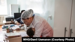 Кызамыкка каршы эмдөө кампаниясы учурунда вакцига алган бала дарыгерди кучактап турат. ДСУ/Данил Усманов
