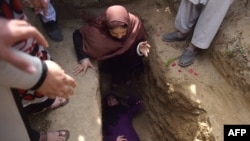 Afghan civil society activist women weep and lie on the grave of Afghan woman Farkhunda, 27, who was lynched by an angry mob in central Kabul in March.