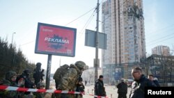Ukrainian servicemen are seen near an apartment building damaged by shelling in Kyiv on February 26.