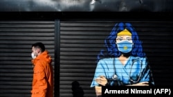 Një person në Prishtinë kalon pranë një murali dedikuar punonjësve shëndetësorë që po punojnë gjatë pandemisë së koronavirusit.