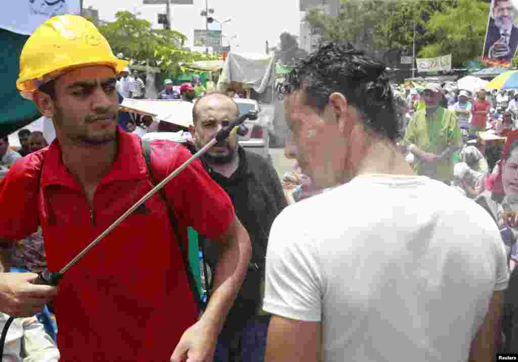 A supporter of ousted Egyptian President Mohamed Mursi is doused with water in sweltering heat during weekly Friday prayers at a protest camp in Cairo's Rabaa Adawiya Square on July 12. (Louafi Larbi)