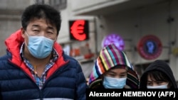 Люди в медицинских масках идут рядом с пунктом обмена валют. Москва, март 2010 года.