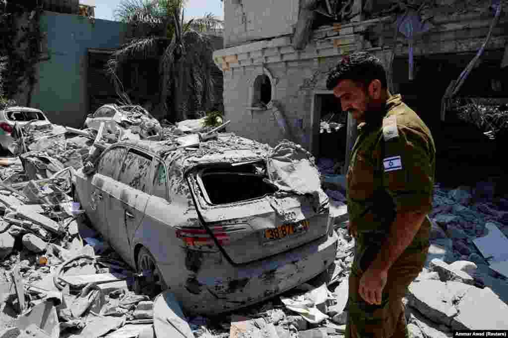 Izraelski vojnik stoji pored oštećenog vozila nakon što su rakete ispaljene iz Irana pogodile stambenu zgradu u Tamri, na sjeveru Izraela, 15. juna.