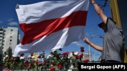 Человек размахивает флагом у места, где в ночь на вторник погиб манифестант. Минск, 11 августа 2020 года.