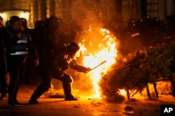 Forțele de ordine încearcă să stingă un incendiu în timp ce susținătorii lui Călin Georgescu protestează după ce BEC a respins candidatura acestuia la reluarea alegerilor prezidențiale.
