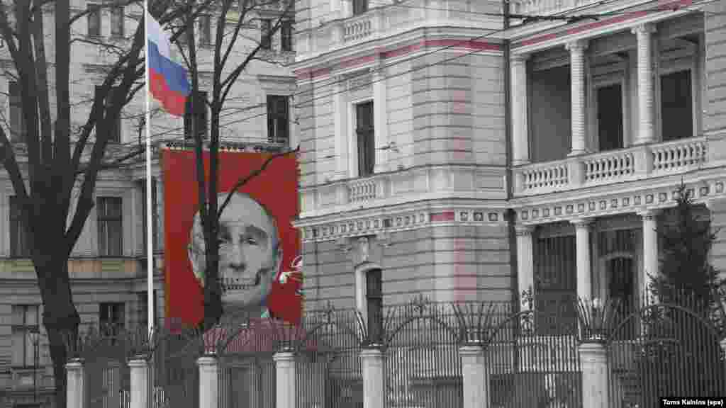Изображение на лицето на руския президент Владимир Путин, половината от което е нарисувано като череп. То е изложено на фасадата на сграда срещу руското посолство в Рига, Латвия, февруари 2023 г.