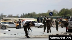 Afghan security forces inspect the site of a bomb explosion near a damaged vehicle in Kabul, April 27, 2020