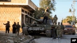 Opozicioni borci stoje pored tenka sirijske vojske u gradu Marat el Numan, jugozapadno od Alepa, Sirija, 30. novembra 2024.