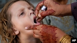 په لاهور کې روغتیايي کارکوونکې یوې ماشومې ته څاڅکي ورکوي - پخوانی انځور.