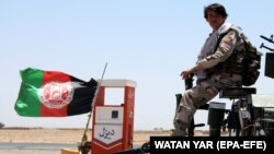 Afghan security officials patrol a highway in Helmand on June 14.