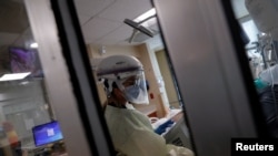 Реаниматолог лечит пациента с коронавирусной инфекцией (COVID-19) в изолированной палате отделения интенсивной терапии (ОИТ) Мемориальной больницы Сарасоты в Сарасоте, Флорида, США, 22 сентября 2021 г.  