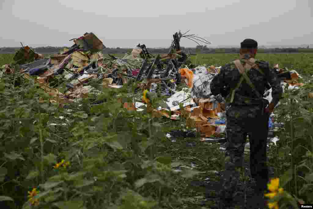 Another pro-Russian separatist looks at wreckage from the nose section of the airliner near the village of Rozsypne on July 18.&nbsp;