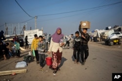 Awatif Abu Jarad duke bartur ujë në një kamp të improvizuar në zonën Muasi, në jug të Gazës. 1 janar 2024.