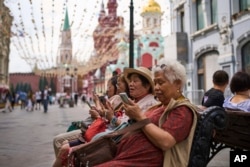 Oameni se uită la telefoane în apropierea Kremlinului din Moscova, 16 iulie 2025.