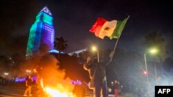 Un protestatar flutură steagul mexican în timpul confruntărilor cu forțele de ordine, în timpul unei manifestații din 8 iunie. 