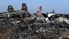 Një grua ec mbi rrënojat e avionit të fluturimit MH17 të Malaysia Airlines, pranë një fshati në rajonin Donjeck të Ukrainës, pasi avioni u rrëzua më 17 korrik 2014.