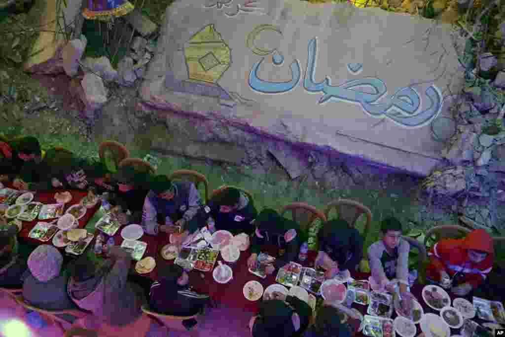 Mbishkrimi "Ramazan", i shkruar arabisht. Palestinezët duke ngrënë syfyrin e parë të shtruar në mënyrë kolektive pranë shtëpive të tyre të shkatërruara në Han Jounis, në jug të Rripit të Gazës, të premten, 28 shkurt 2025.&nbsp;