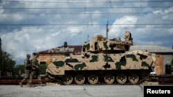 Ushtarët amerikanë kalojnë pranë një automjeti luftarak të këmbësorisë, Bradley. Fotografi ilustruese nga arkivi. 