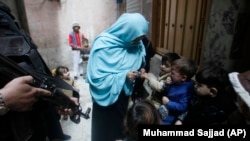 A policeman guards a health worker as she gives a polio vaccination to a child in Peshawar on December 16.