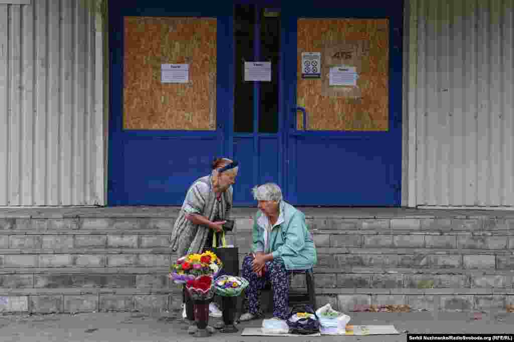 Gratë duke shitur lule dhe perime pranë një dyqani të madh të mbyllur. Në Pokrovsk, të gjitha dyqanet e mëdha dhe qendrat tregtare janë të mbyllura. Vetëm dyqanet e vogla ushqimore mbeten të hapura.