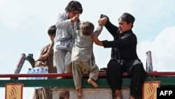 افغان ماشومان ننګرهار ته تر رسېدو وروسته یو ماشوم لارۍ ته خېژوي - د اپرېل ۲۰مې انځور.