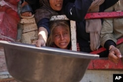 Palestinienii se luptă pentru a obține alimente donate la o cantină comunitară, în orașul Gaza, în nordul Fâșiei Gaza, sâmbătă, 26 iulie 2025.