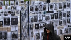 Мужчына ідзе паўз выставу партрэтаў беларускіх палітвязьняў у цэнтры Варшавы 18 траўня 2025 году