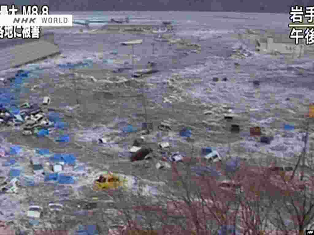 Japan--screen grab shows cars and containers floating in a massive tsunami wave to have hit Sendai, 11Mar2011 - Скриншот выпуска новостей телекомпании NHK  11 марта 2011. Вагоны и контейнеры плавают в волне цунами. JAPAN OUT AFP PHOTO / HO / NHK