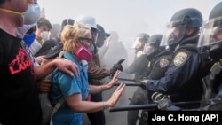 Протестующие противостоят полиции на шоссе 101 возле Центра заключения в Лос-Анджелесе после иммиграционного рейда протеста. Фото AP