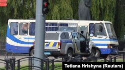 Правоохоронці лежать на землі за автомобілем біля пасажирського автобуса, захопленого зловмисником у Луцьку, 21 липня 2020 року