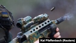 Припадник на украинските специјални сили тестира оружје пред мисијата во регионот Бахмут , 6 април 2023.