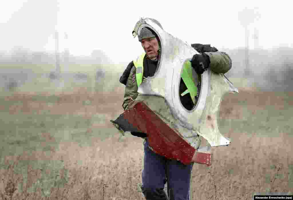 A November 2014 photo of a man carrying a piece of the aircraft from the crash site inside Ukrainian territory held by Russia-backed separatists. Dutch inspectors commissioned the emergency services of the separatist group that calls itself the Donetsk People's Republic to collect the wreckage after saying the area was too dangerous for their staff.&nbsp;