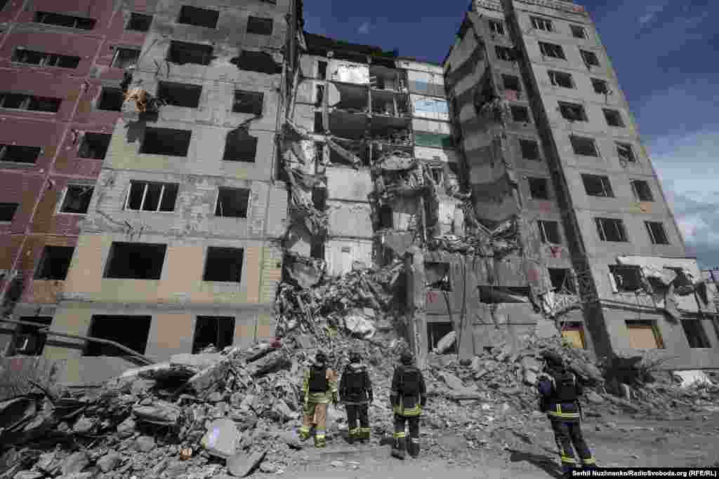 Pompieri și salvatori ucraineni, în fața unui bloc lovit de o bombă ghidată lansată de forțele ruse.