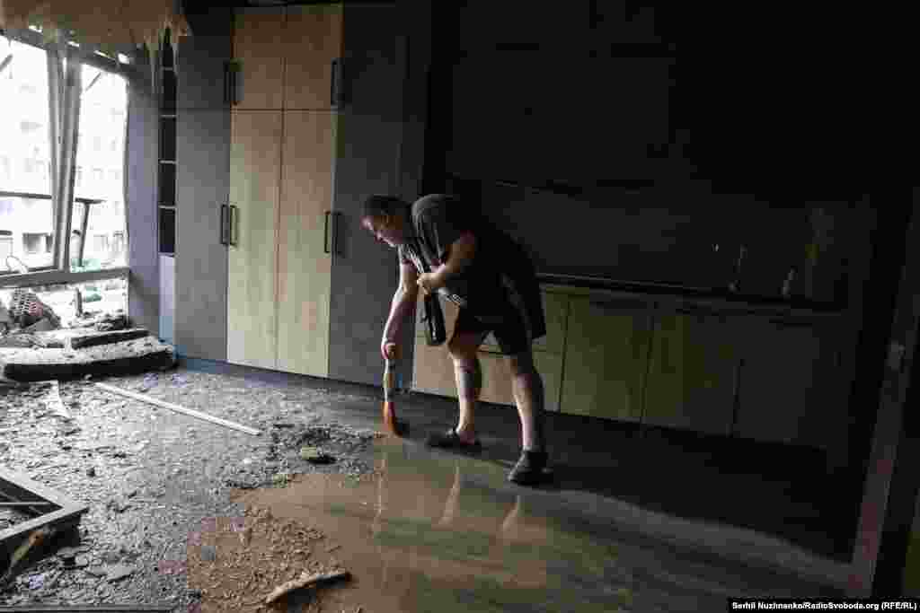 Një burrë pastron brenda ndërtesës së dëmtuar në lagjen Shevçenkivski.