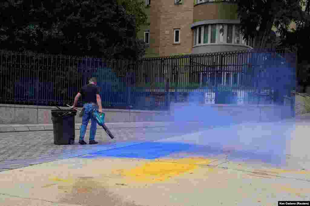 მამაკაცი შლის უკრაინის დროშის ფერების საღებავებს, ვაშინგტონში, რუსეთის საელჩოს წინ, 2025 წლის აგვისტოში. ქუჩა შეღებეს ალასკაში ტრამპ-პუტინის წარუმატებელი მოლაპარაკებების წინ, რომელიც ომის დასრულებისკენ იყო მიმართული.