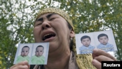 An ethnic Uzbek refugee shows photos of her missing grandsons as she stands on the Kyrgyz-Uzbek border on June 15.