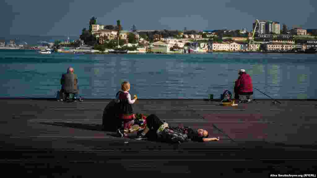 Містяни відпочивають на дерев'яному помості біля Севастопольської бухти