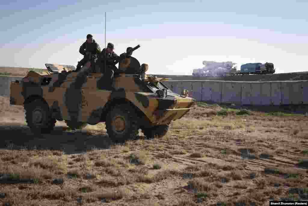 "Союз" зымыранын ұшу алаңына апара жатқанын беренді техника үстінде бақылап отырған ресейлік әскерилер.