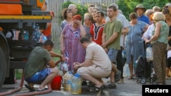 Residents wait in line to collect water delivered by a tank truck in Donetsk on July 29.
