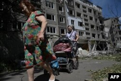 Localnicii își transportă bunurile dintr-un bloc avariat în urma unui atac rus în orașul Bilozerske, regiunea Donețk, pe 12 august 2025.