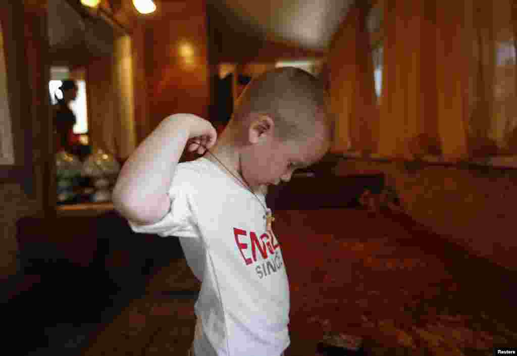 A child puts on an Orthodox cross in temporary accommodation in the town of Nyzhnya Krynka.