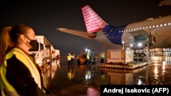 Работници истоваруваат контејнери со 500.000 дози кинески вакцини „Синофарм“ од специјалниот лет на „Ер Србија“ на аеродромот во Белград, 10 февруари 2021 година