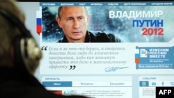 A man looks at a computer monitor displaying the main page of Prime Minister Vladimir Putin's election campaign website.